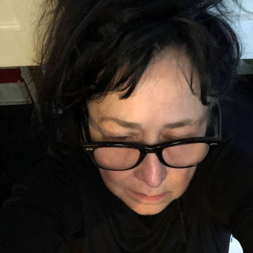 Dara Wier in a downward angled selfie wearing a black shirt and glasses.