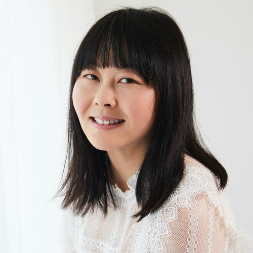 Lang Leav seated in front of white background wearing lacy white shirt.