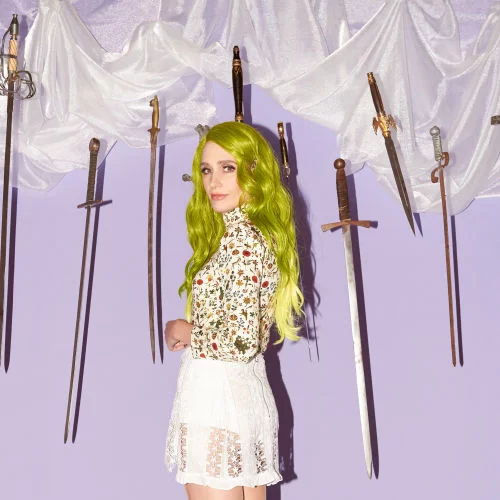 Portrait of Sadie Dupuis in front of lavendar wall with hanging swords.