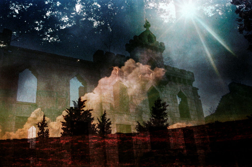 A photographic print of a gothic cathedral shot from an ant’s eye view. The print has several images layered, all of which are translucent. Over the cathedral is a large white cloud and in the foreground there are four pine trees, which are a dark red. The background is a dense forest canopy with spots of light trickling through the leaves.